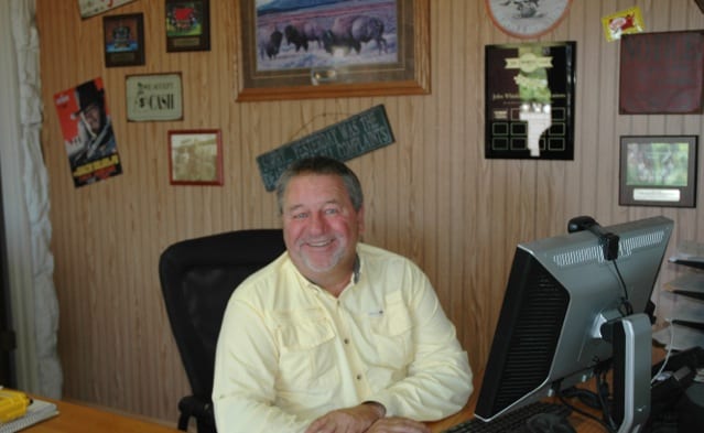 A man sitting at his desk in front of a laptop.