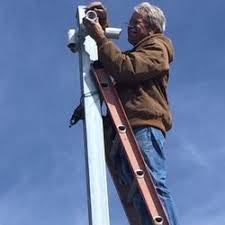 a man on a ladder is installing CCTV cameras