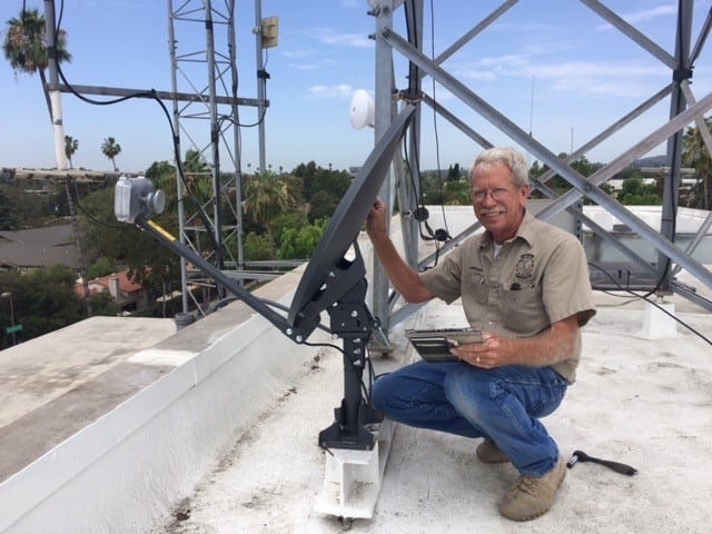 A man on the roof of a building with an antenna.