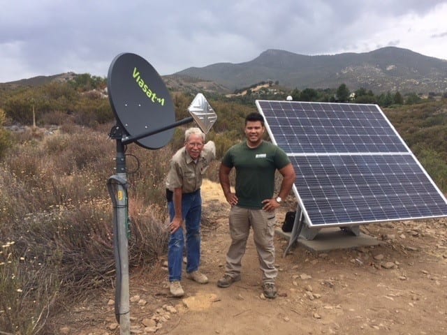two men standing near a solar panel